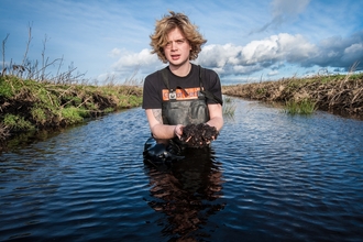 Filip stands in the water holding mud