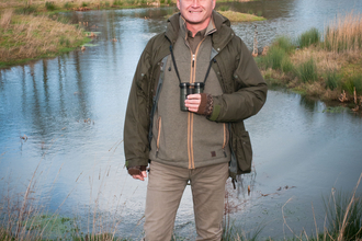 Simon King standing in front of a pond