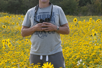 Iolo stands in a field of sunflowers