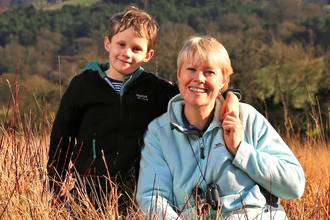 Kati and her son sat in a field with woods in background