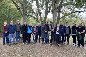 Group of adults standing side by side in a line under trees