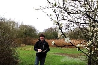 Nathanael stands in a partially flooded grass meadow with tree surrounding