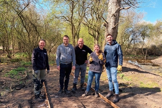 Volunteers from Supported Steps with Great Fen reserves team members stand by the path frame they've installed