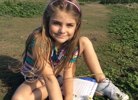 Grace sits in the grass with flowers