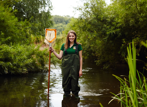 Sophie standing in a river with a net