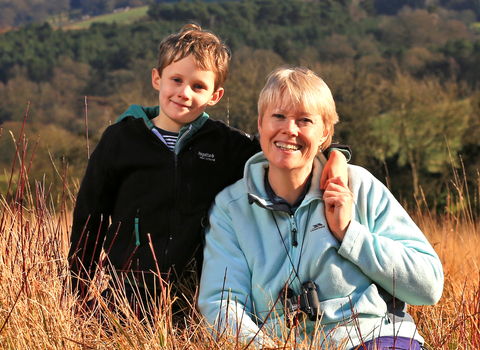 Kati and her son sat in a field with woods in background